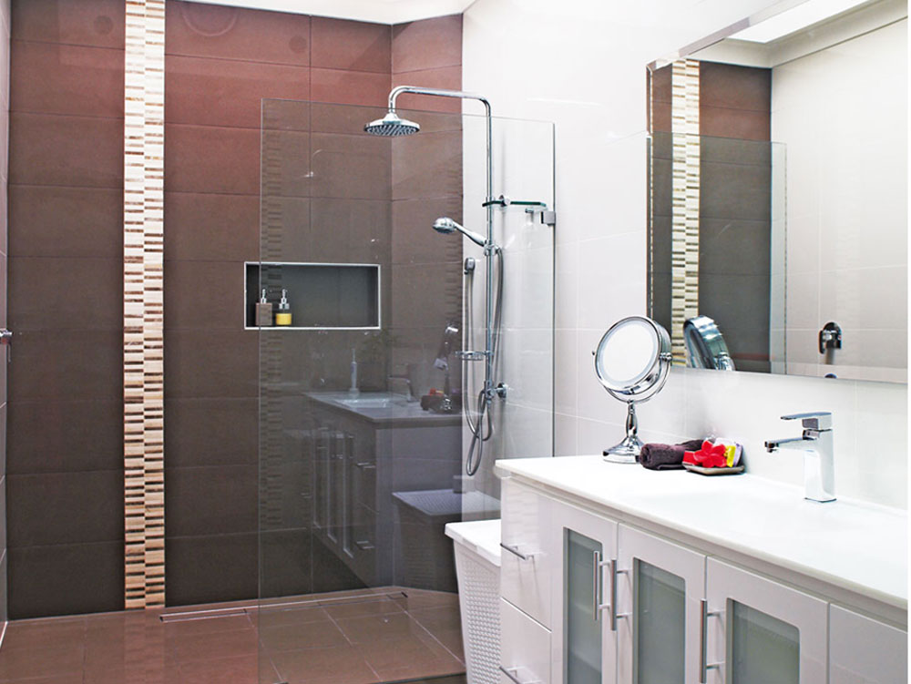 a renovated bathroom with brown tiles and white cabinetry